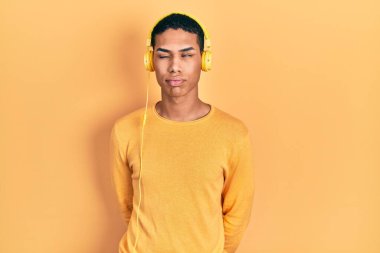 Genç Afrikalı Amerikalı adam kulaklık takıyor. Uykulu ve yorgun görünüyor. Yorgun ve akşamdan kalma, tembel gözlü.. 