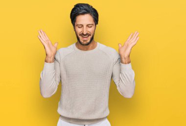 Gündelik kıyafetler giyen genç İspanyol adam başarı için deli ve çılgınlığı kutluyor kollarını kaldırmış ve gözlerini kapatmış heyecanla bağırıyor. Kazanan konsept 