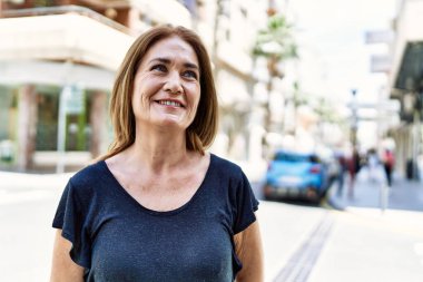 Orta yaşlı İspanyol kadın güneşli bir günde mutlu bir şekilde gülümsüyor.