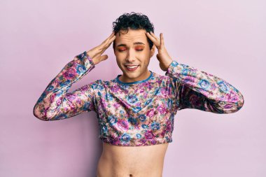 Makyaj yapan yakışıklı bir adam, stresten dolayı başı ağrıyan moda kıyafetleri giyiyor. migren ağrısı. 