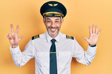 Yakışıklı, orta yaşlı, gri saçlı, uçak pilotu üniforması giyen, 8 numaralı parmaklarıyla işaret eden, kendinden emin ve mutlu bir adam.. 