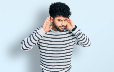 Sıradan çizgili süveter giyen sakallı genç Arap adam iki elini de kulak hareketi yaparken duymaya çalışıyor, dedikoduya meraklı. İşitme sorunu, sağır 