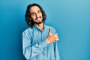Gündelik kıyafetler giyen genç İspanyol adam elleriyle mutlu bir jest yapıyor. Kameraya bakıp başarıyı gösteren ifade. 