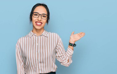 Gündelik kıyafetler ve gözlük takan, neşeli gülümseyen, avuç içi kameraya bakan genç İspanyol kız.. 