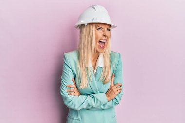 Mimar şapkalı genç sarışın kadın kızgın ve kızgın bağırıyor sinirli ve öfkeli, öfkeyle bağırıyor. öfke ve agresif konsept. 