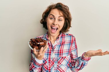 Genç esmer kadın elinde kaseyle zaferi kutluyor. Gülümsüyor ve kazanan el kaldırıyor. 