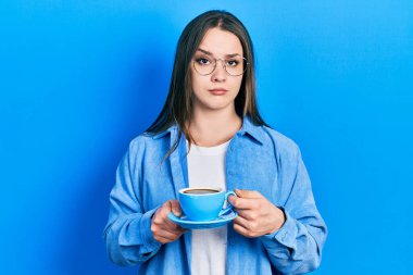 Latin kökenli genç bir kız bir fincan kahve içiyor şüpheci ve gergin, sorun yüzünden surat asıyor. negatif kişi. 
