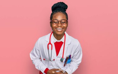 Genç Afro-Amerikan kadın doktor üniforması ve steteskop giyip kahkahalarla gülüyor.. 