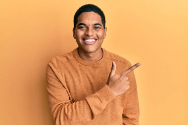 Genç, yakışıklı İspanyol bir adam, günlük kışlık süveter giyiyor. Neşeli, yüzünde mutlu ve doğal bir ifadeyle, elleri ve parmaklarıyla yüzünü gösteren bir gülümseme var. 