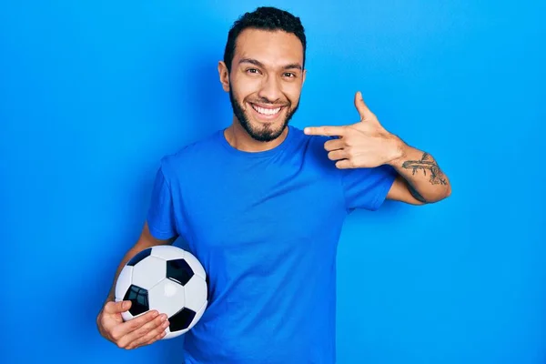 Hiszpan Brodą Trzymający Piłkę Nożną Uśmiecha Się Radośnie Pokazując Wskazując — Zdjęcie stockowe