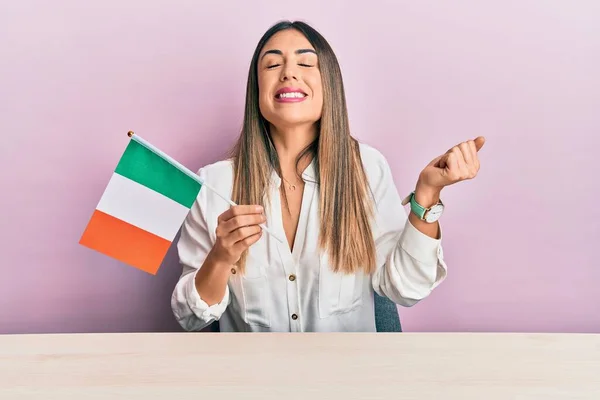 Ung Latinamerikansk Kvinna Håller Irländsk Flagga Sitter Bordet Skrikande Stolt — Stockfoto