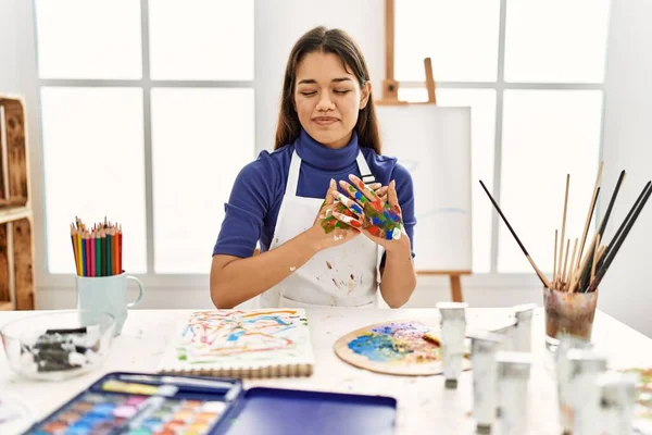 在艺术工作室里 年轻的黑发女人 手绘着画 双手紧闭着眼睛 脸上挂着感恩的手势 微笑着 健康概念 — 图库照片