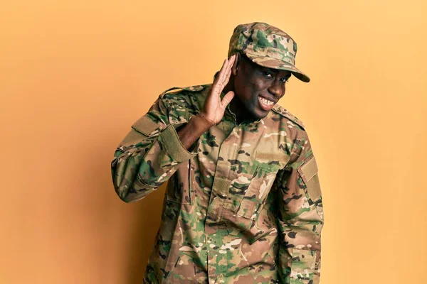 軍の制服を着た若いアフリカ系アメリカ人男性が 噂やゴシップに耳を傾けながら手で笑っている 聴覚障害の概念 — ストック写真
