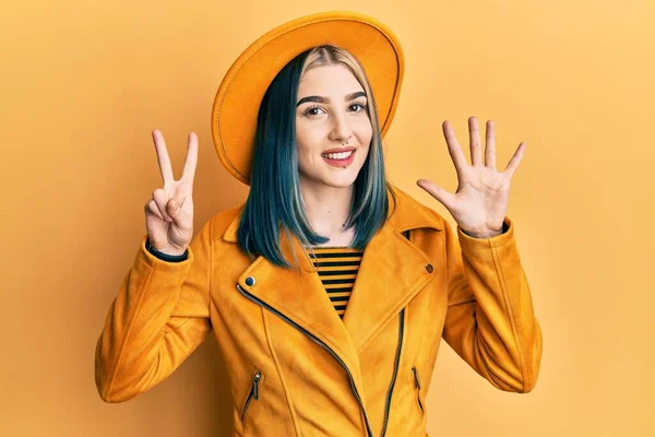 모자와 자켓을 손가락을 고개를 자신감 미소를 현대의 아가씨 — 스톡 사진