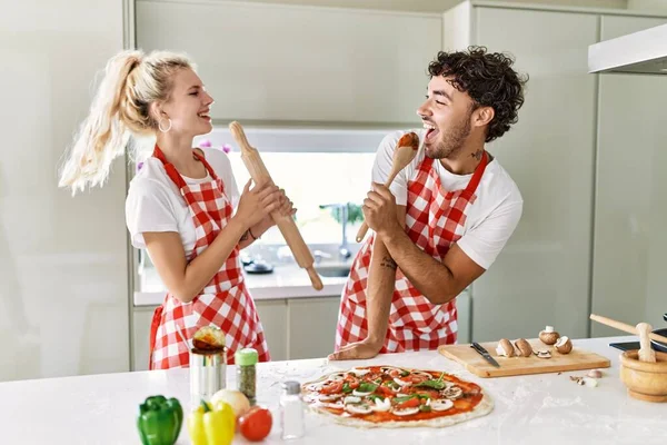 若いカップルは キッチンでマイクとして膝とスプーンを使用して幸せと歌を笑っています — ストック写真