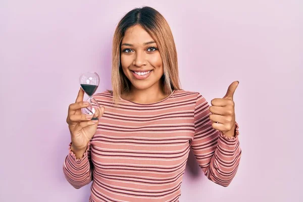 Hermosa Mujer Hispana Sosteniendo Reloj Arena Sonriendo Feliz Positivo Pulgar —  Fotos de Stock