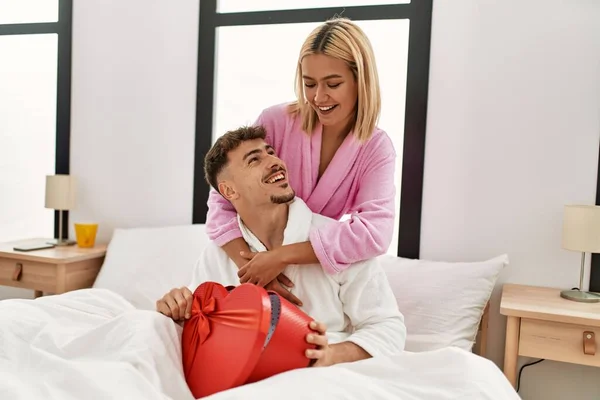 Kvinna Överraskar Sin Pojkvän Med Valentine Presentförpackning Sitter Sängen Hemma — Stockfoto