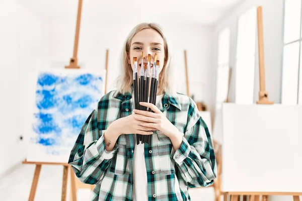 在艺术工作室 年轻的女艺术家高兴地微笑着 手里拿着画笔蒙着脸 — 图库照片