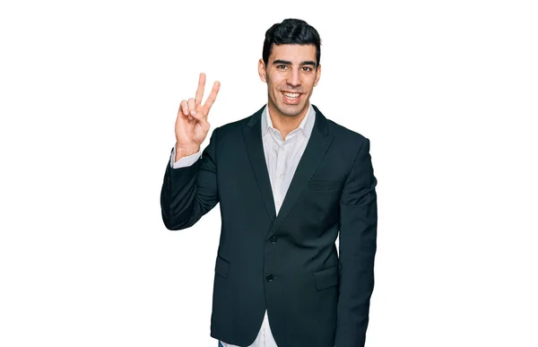 ビジネス用の服を着たハンサムなヒスパニック系の男性が 指の勝利の兆候を示すカメラを見て笑っている — ストック写真
