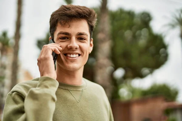若いヒスパニック系の男は 市内のスマートフォンで幸せな話を笑って — ストック写真