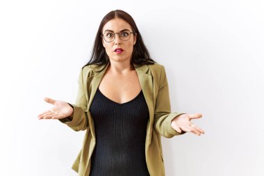 Soyutlanmış arka planda duran esmer bir kadın. Hiçbir fikri olmayan, kolları açık, kafası karışık bir kadın.. 