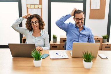 Orta yaşlı İspanyol bir kadın ve laptopuyla ofiste oturan bir adam soru sorup şaşırıyorlar. Şüpheyle kararsız, kafa kafaya düşünerek. Düşünceli kavram. 