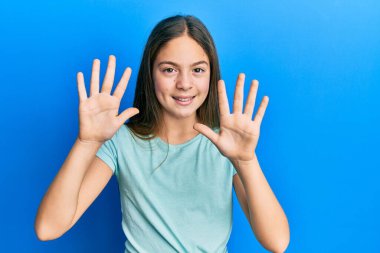 Güzel esmer, beyaz tişört giyen küçük bir kız on numarayı gösterip işaret ederken kendinden emin ve mutlu gülümsüyor.. 