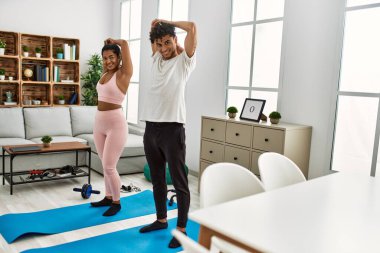 Genç Latin sporcu çift gülümseyerek evde mutlu bir antrenman yapıyor..