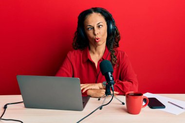 Radyo stüdyosunda çalışan orta yaşlı güzel bir kadın dudaklarıyla balık suratı yapıyor, çılgınca ve komik bir jest. Komik ifade. 