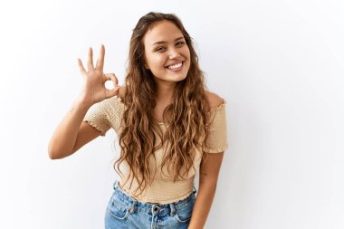 Güzel İspanyol kadın tecrit edilmiş bir şekilde dikilirken arka planda gülümsüyor ve el ve parmaklarıyla 