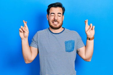 Sakallı, sıradan çizgili tişört giyen yakışıklı beyaz adam umut ve gözleri kapalı gülümseyerek el sallıyor. Şans ve batıl inançlar. 