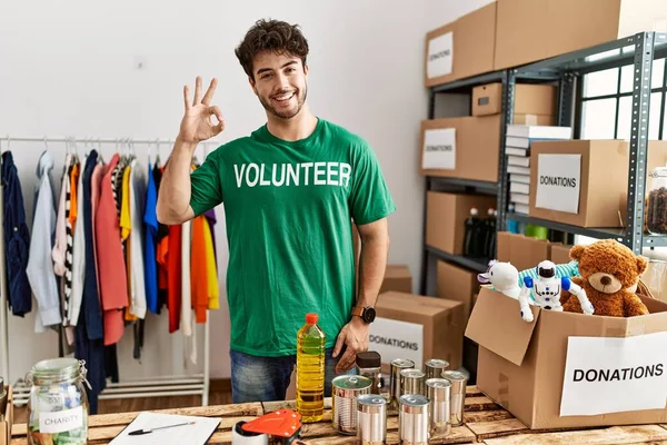 Hombre Hispano Vistiendo Camiseta Voluntaria Stand Donaciones Haciendo Signo Con —  Fotos de Stock