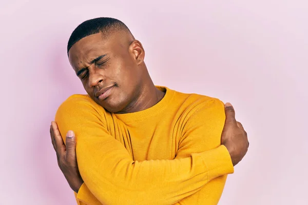 Young Black Man Wearing Casual Yellow Sweater Hugging Oneself Happy — Stock Photo, Image