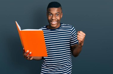 Genç Afrikalı Amerikalı adam elinde kitapla gururla bağırıyor zaferi ve başarıyı kutluyor. 