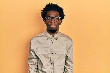 Genç, Afro-Amerikalı bir adam günlük kıyafetler ve gözlük takıyor. Depresyonda ve endişe içinde. Kızgın ve korkmuş. hüzünlü ifade. 