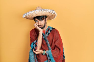 Meksikalı şapkalı genç İspanyol adam kollarını kavuşturup depresyondan sıkılmış ve yorgun görünüyor.. 