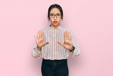 Gündelik kıyafetler giyen ve gözlüklü genç İspanyol kız ellerini kaldırıyor. Avuçlar reddediyor ve reddediyor. Korkmuş ve iğrenç bir ifadeyle. Dur ve yasakla. 