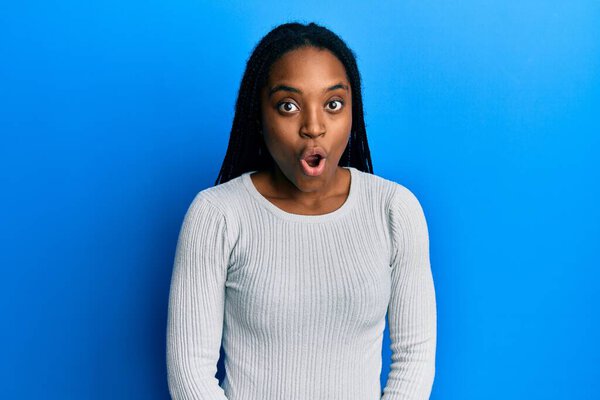 African american woman with braided hair wearing casual white sweater afraid and shocked with surprise expression, fear and excited face. 