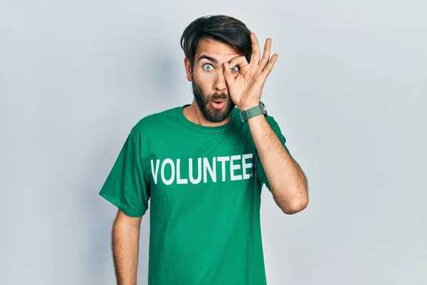 Jovem Hispânico Vestindo Camiseta Voluntária Fazendo Gesto Chocado Com Rosto — Fotografia de Stock