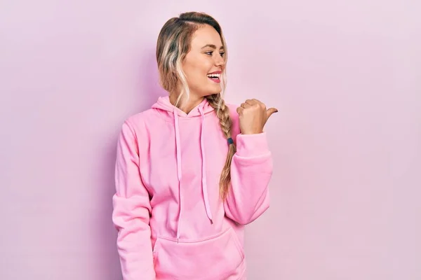 Mooie Jonge Blonde Vrouw Dragen Roze Sweatshirt Wijzen Duim Naar — Stockfoto