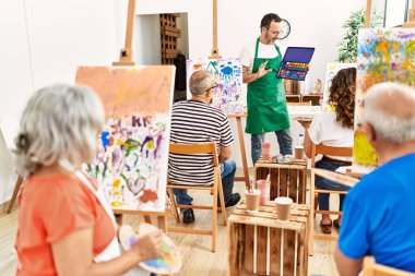 Bir grup orta yaşlı öğrenci resim stüdyosunda resim dersi alıyor..