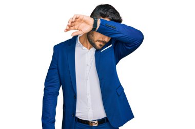 Genç İspanyol bir adam iş ceketi giyiyor, gözleri kollarıyla kapatıyor, ciddi ve üzgün görünüyor. Görme, saklama ve reddetme konsepti 