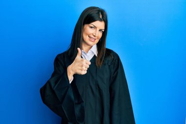 Yargıç üniforması giyen genç İspanyol kadın elleriyle mutlu bir jest yapıyor. Kameraya bakıp başarıyı gösteren ifade. 