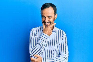 Orta yaşlı İspanyol bir adam gündelik kıyafetler giyiyor kameraya bakıyor kollarını kavuşturup gülümsüyor ve çenesini kaldırıyor. Olumlu düşünmek. 