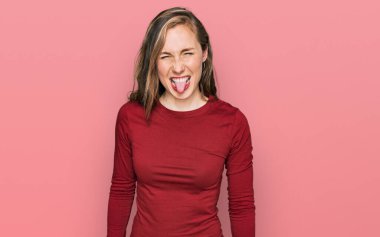 Sıradan kıyafetler giyen genç sarışın kadın komik bir ifadeyle dilini dışarı çıkarıyor. duygu kavramı. 