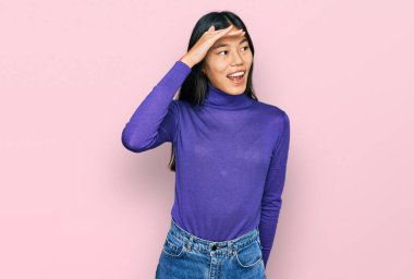 Güzel, genç Asyalı bir kadın gündelik giysiler giyiyor çok mutlu ve gülümsüyor başlarını kaldırıp uzaklara bakıyor. arama kavramı. 