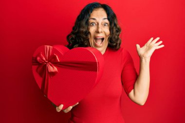 Orta yaşlı İspanyol kadın sevgililer günü hediyesi tutuyor zaferi mutlu bir gülümsemeyle kutluyor ve kazanan el kaldırarak ifade ediyor. 