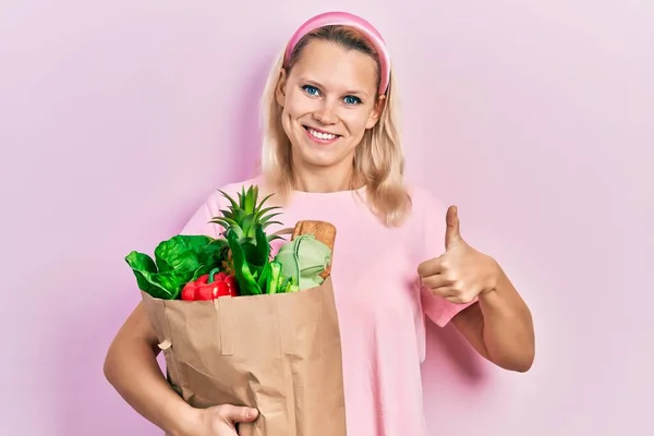 Krásná Běloška Blondýnka Drží Papírový Sáček Potravinami Usmívá Šťastně Pozitivně — Stock fotografie