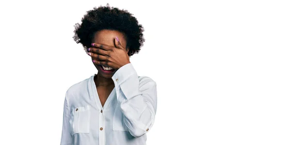 アフロの髪をしたアフリカ系アメリカ人の女性は カジュアルな白いTシャツを着て笑顔で 驚きのために目を覆う顔を手で笑っています 視覚障害の概念 — ストック写真