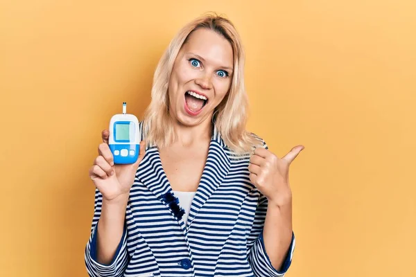 Mooie Kaukasische Blonde Vrouw Houden Glucometer Apparaat Wijzen Duim Naar — Stockfoto